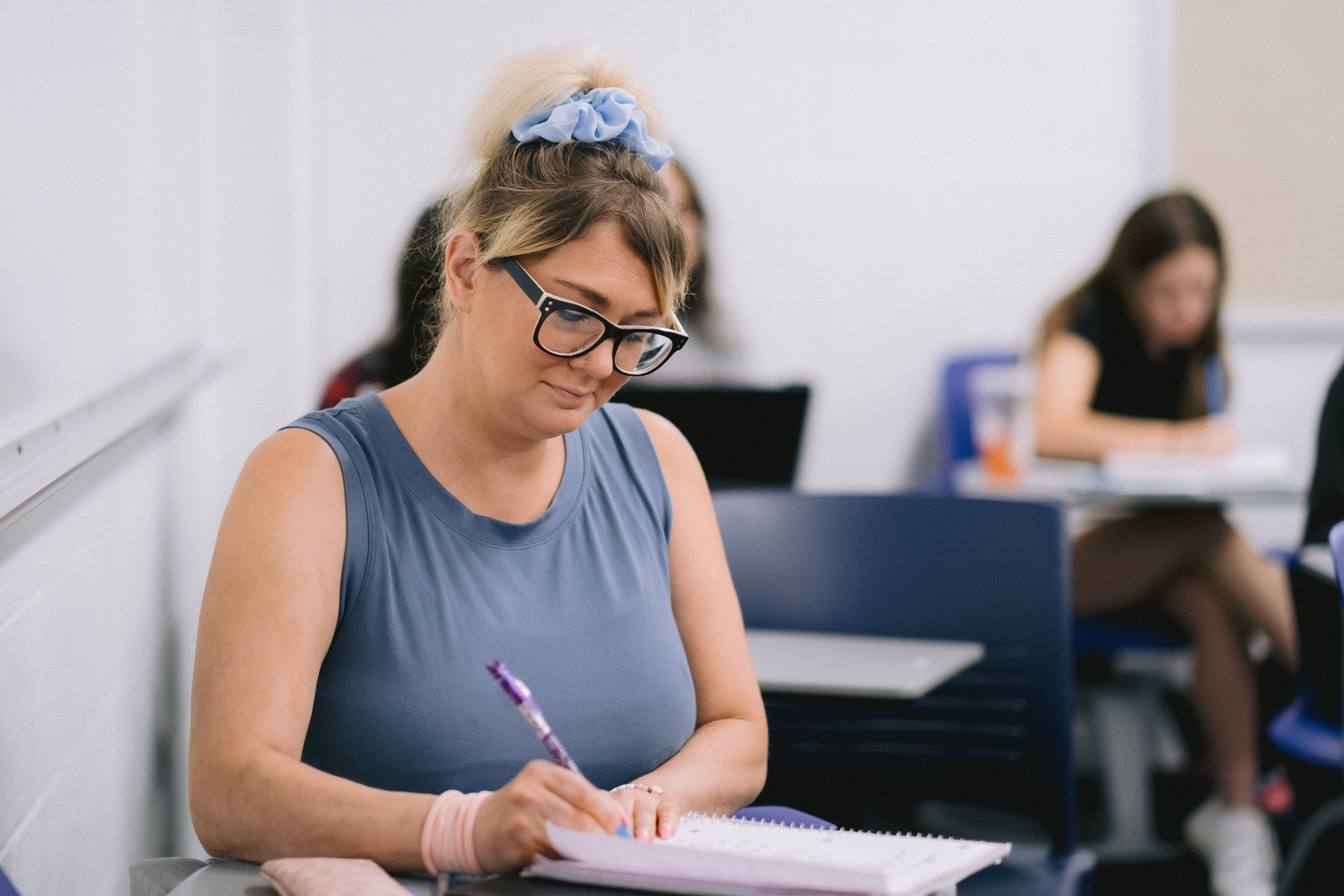 Adult student taking notes during class.
